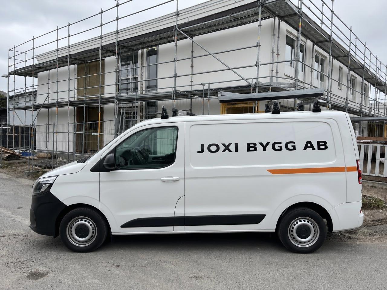 Servicebil profilerad med Joxi Bygg AB vid en ordnad byggarbetsplats